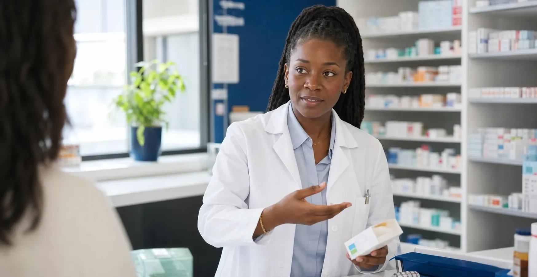 Une pharmacienne noire échange avec une consœur au comptoir d’une officine