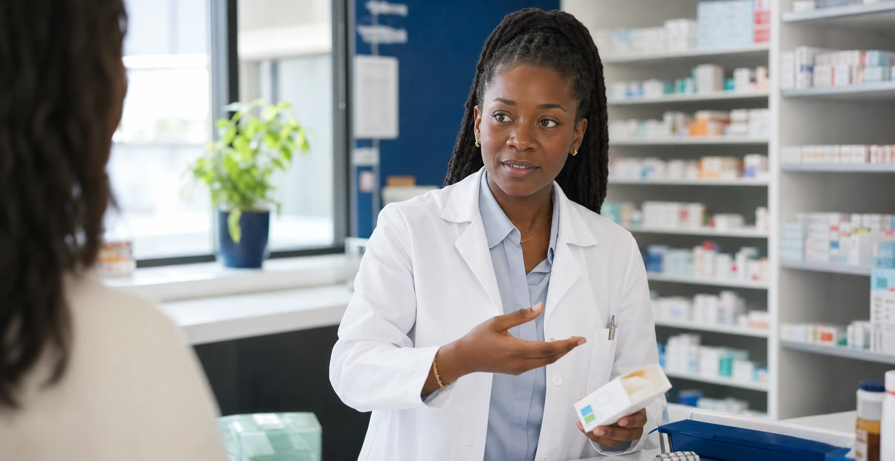 Une pharmacienne noire échange avec une consœur au comptoir d’une officine